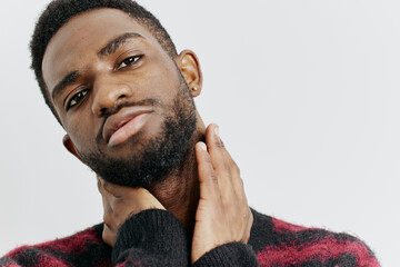 Pensive young man in a red and black sweater with hands on his face, gazing thoughtfully at the...