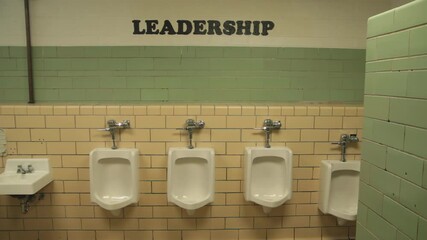 High school Male bathroom with urinals and leadership sign