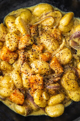 turmeric gnocchi with pumpkin and onion in creamy sauce, healthy plant-based food