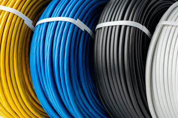Four Spools of Electrical Wire in Yellow, Blue, Black, and White Colors: A Close-Up Photo of Four...