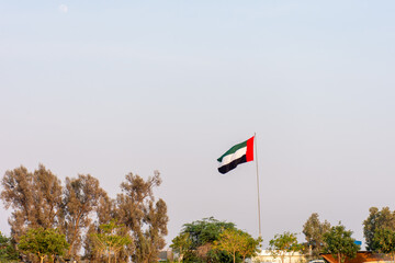 UAE flag waving against the sky in Dubai City, UAE.