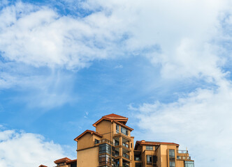 Below the blue sky and white clouds is the roof of the house.