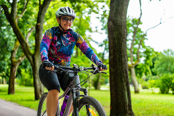 Cycling training in city. Young joyful woman in white helmet and colorful blouse and black shorts...