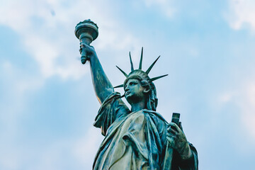 Fototapeta premium Statue of Liberty holding torch against blue sky symbolizes freedom and democracy