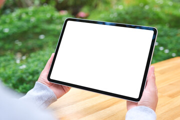 Mockup image of a woman holding digital tablet with blank white desktop screen in the outdoors