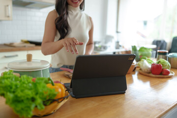 Beautiful Asian woman practicing making vegetable salad Fruits are eaten in a relaxed way at home. View social media online on laptop healthy eating Weight loss and dieting healthy food concept.