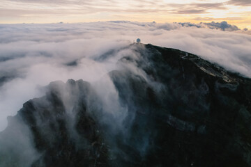 Naklejka premium Aerial view of majestic mountain ridges at sunrise with falling fog from top of Pico do Areeiro, Madeira island, Portugal