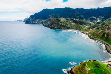 Fototapeta premium Aerial view of rough ocean with waves, volcanic beach in Porto da Cruz, Madeira, Portugal