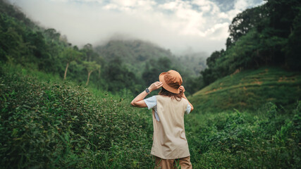 Happy young asian tourist female standing in meadow with mountains and fog at Khao Chong Lom new landmark of Thailand, Carefree woman in fields and stream, Rest on vacation holiday weekend