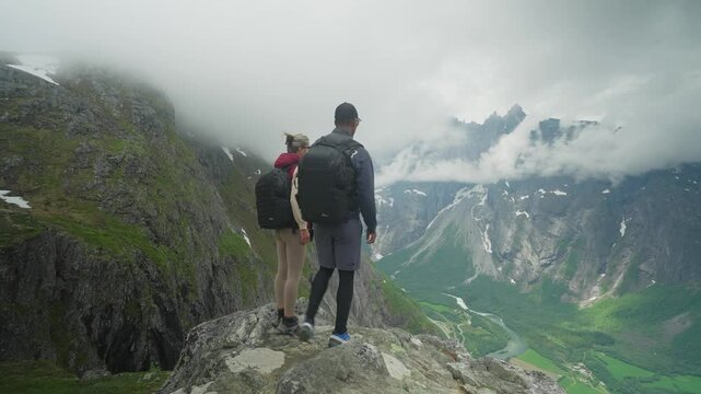 Two hikers trekking in Norway with a stunning view of Trollveggen and the valley below