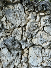 Masonry wall made of uneven gray stones, vertical abstract background