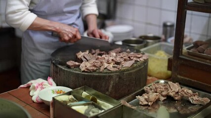 Slow-motion video of a Taiwanese woman rapidly cutting meat in a street food stall kitchen in Taipei, Taiwan
台湾台北市の屋台の厨房で台湾人女性が高速でお肉を切るスローモーション映像