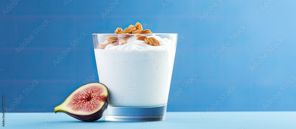 Poster Glass of yogurt with fig fruit slices on blue background in a horizontal copy space image. Daylight illuminating the scene.