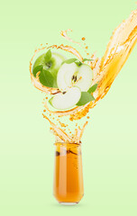 Flow of apple yellow cold juice pouring in glass with levitated green apples, leaves, splashes,...