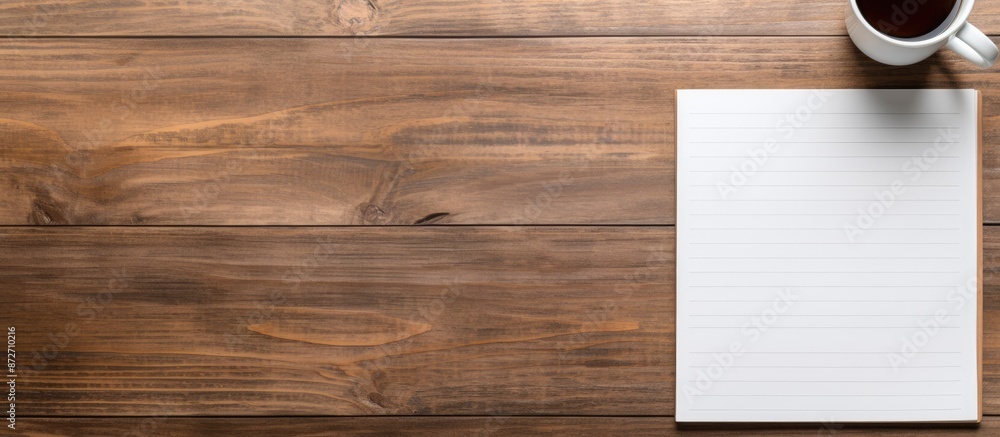 Poster Wooden desk in an office setting featuring a blank notepad, pen, and coffee cup on it. Top-down flat lay view with available space for adding an image. with copy space image