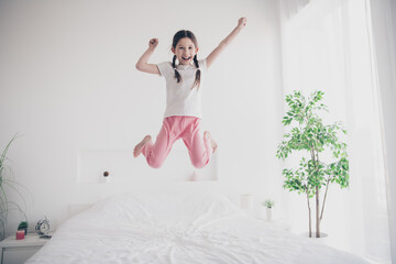 Full body portrait of adorable small girl jump wear pajama comfy bed bedroom apartment indoors