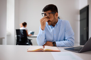 Obraz premium Exhausted businessman having headache while working in the office.