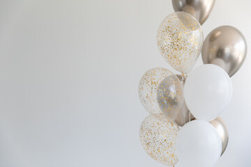 Golden balloons and balloons with glitter on white background on the right. Copy space.