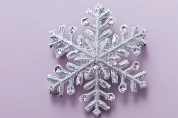 A glittering silver snowflake ornament, isolated on a light purple background.
