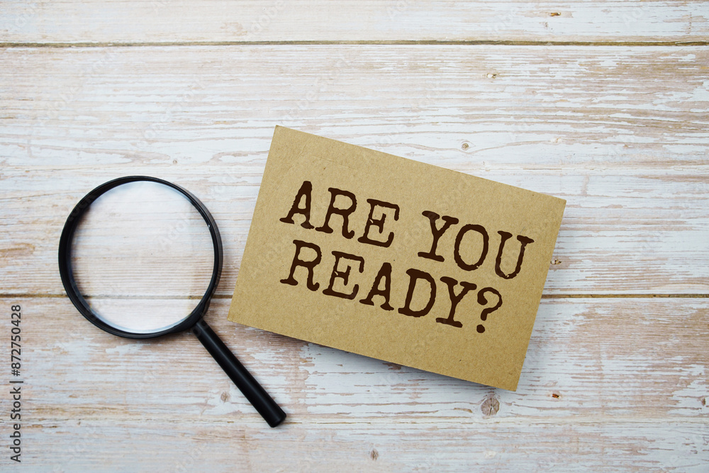 Poster are you ready? text message and magnifying glass with space copy on wooden background