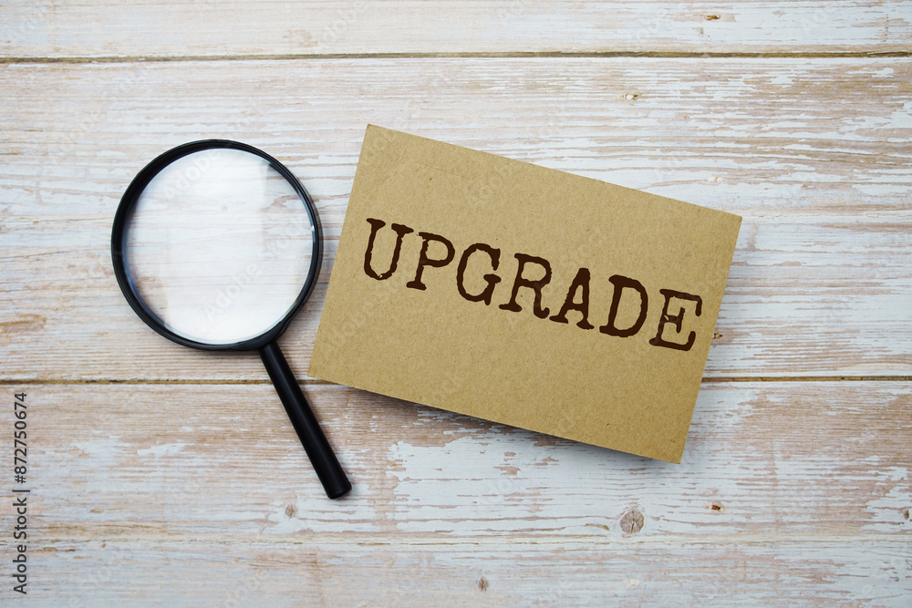 Poster upgrade text message and magnifying glass with space copy on wooden background