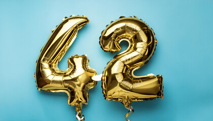 Banner with number 42 golden balloon. 42 years anniversary celebration. Blue background. Close-up.
