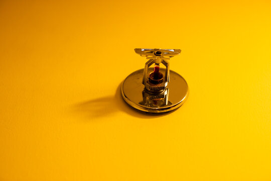 Springer extinguishes pelling on yellow wall.Wireless smoke detector fire alarm ceiling mounted.
