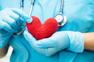 Doctor holding a red heart in hospital ward, healthy strong medical concept.