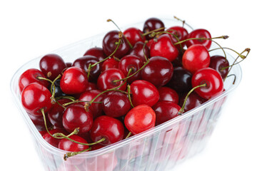 Pile of fresh ripe sweet cherry berry, fruit in transparent plastic box isolated on white background