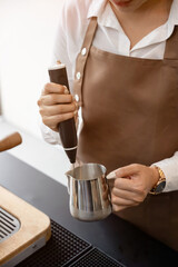 Female barista in apron using blender to froth milk Making coffee for customers in a coffee shop ,small business idea