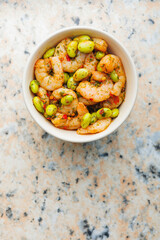 Fresh salad with shrimps and edamame soybeans in bowl on kitchen table. Top view.