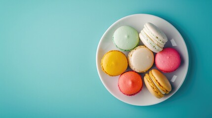 Obraz premium Colorful macarons on white plate against blue background top view close up