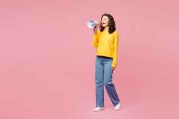 Full body young woman wearing yellow sweatshirt casual clothes hold in hand megaphone scream announces discounts sale Hurry up isolated on plain pastel light pink background studio. Lifestyle concept.