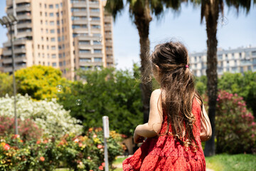 Girl in Red Dress Back View Among Soap Bubbles in the Park