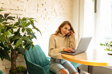 Woman freelancer using laptop while sitting in cozy cafe. Concept for education, business. Shopping online.