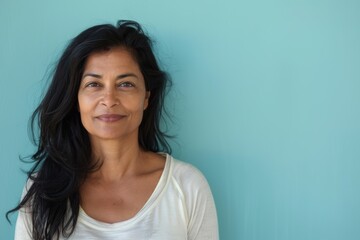 Fototapeta premium Portrait of a blissful indian woman in her 40s sporting a long-sleeved thermal undershirt in pastel blue background