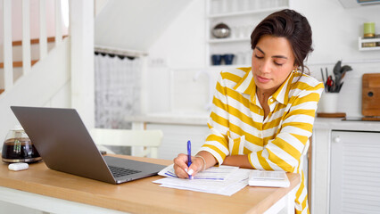 Beautiful, young woman managing her finances at home