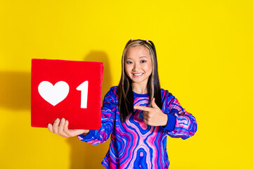 Portrait of cheerful girlish woman with dyed hairstyle dressed print shirt indicating at red like box isolated on yellow color background