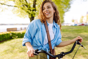 Obraz premium Happy woman riding bicycle bike in the park outdoors. Active urban healthy lifestyle concept