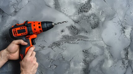 Naklejka premium Builder s hand holding hammer drill against gray wall with space for text