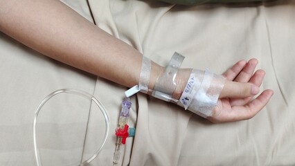 Portrait patient lying on the bed, Saline in hand and during lying rehabilitation in the hospital, health care and medical concept.