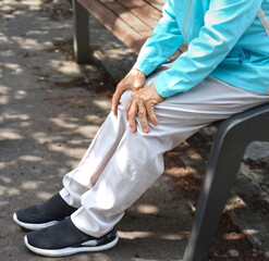Elderly woman holding her knee with her hand due to pain caused by osteoarthritis
