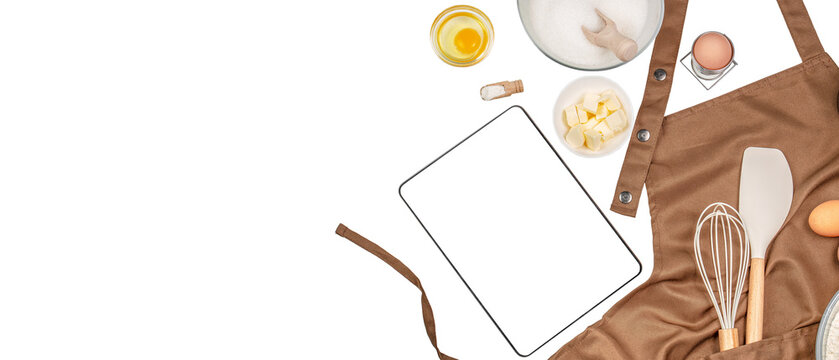 digital tablet computer apps with baking ingredients and utensil on kitchen table, top view