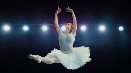 Skilled Ballet Dancing Ballerina in White Tutu Performs High Grand Jeté Under Bright Stage Lights,...