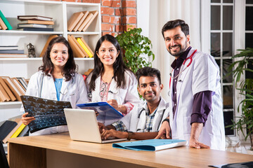 Fototapeta premium Indian asian four young doctors discussing with laptop and case file at table