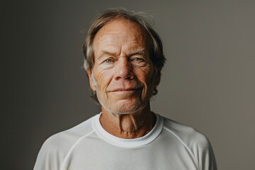 Obraz premium Portrait of a satisfied caucasian man in his 50s sporting a breathable mesh jersey over soft gray background