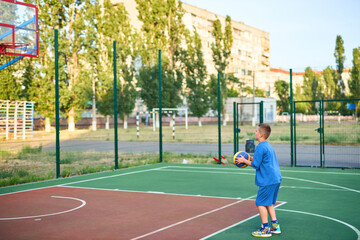 Fototapeta premium caucasian little basketball player jumps to throw the ball into the basket hoop
