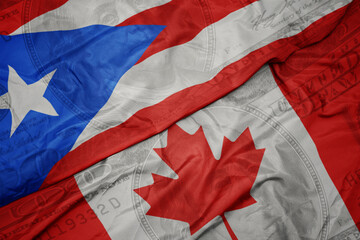 waving colorful flag of puerto rico and national flag of canada on the dollar money background....