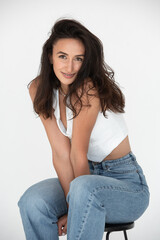 Happy beautiful girl posing in a new hot summer look. Wearing blue jeans and white waistcoat