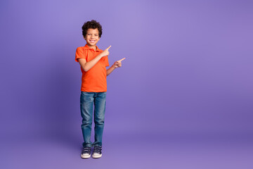 Full length photo of attractive funny grandson wear orange polo shirt pointing two fingers emtpy space isolated purple color background